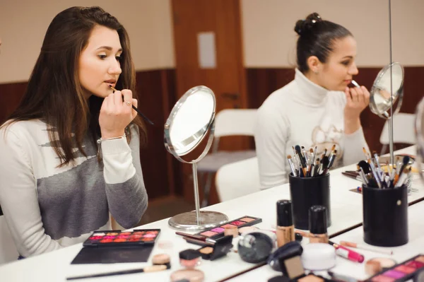 School of makeup. Make up artist doing professional make up of young woman.