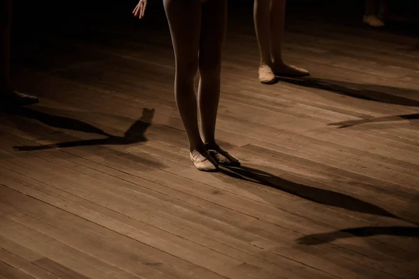 Feet of dancing ballerina on a dark lighted scene.