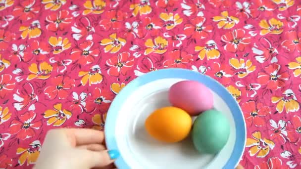 Вона одягає рожеву скатертину тарілку з барвистими великодніми яйцями . — стокове відео