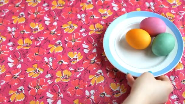 Ella pone en un platillo de mantel rosa con huevos de colores, pastel de Pascua y cuchara . — Vídeos de Stock