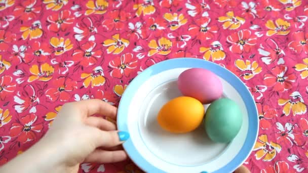 Ella pone en un platillo de mantel rosa con huevos de colores y pastel de Pascua . — Vídeos de Stock