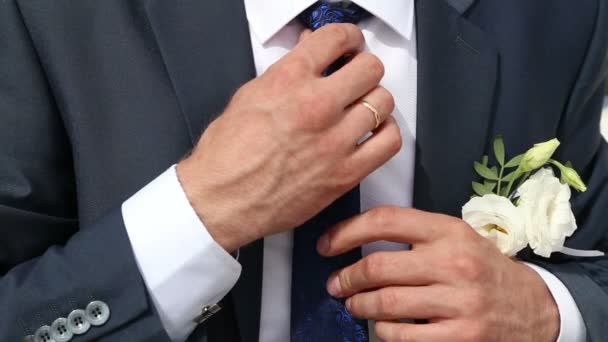 Man (groom) straightens his tie and fasten jaket — Stock Video