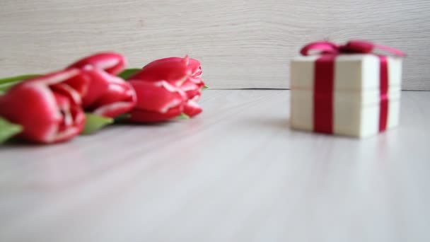 Rood-witte tulpen en geschenkdoos met strik op de witte tabel — Stockvideo