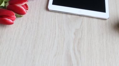 Lale, tablet ve hediye kutusu beyaz bir masanın üzerinde yatan.