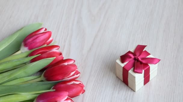 Fehér asztal található tulipán piros-fehér és piros Ajándékdoboz.