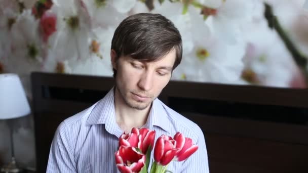 Handsome man looking at flowers - tulips and presents them in the camera — Stock Video