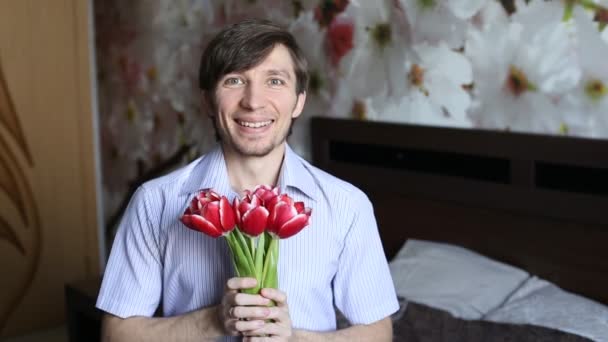 Mooie man met genegenheid presenteert bloemen naar de camera - de tulpen. — Stockvideo