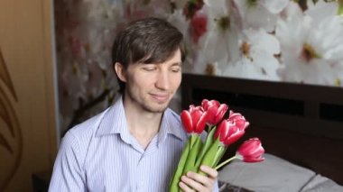 Çekici bir adam bir öpücük gönderir ve çiçek verir.