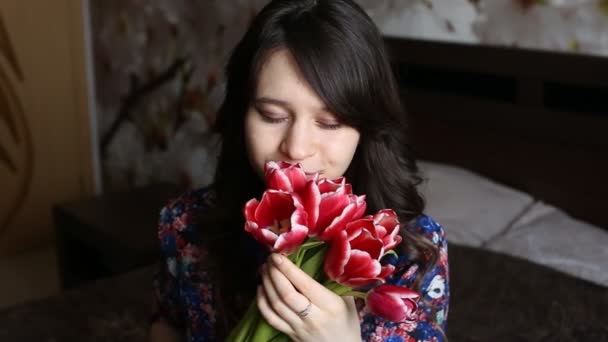 Όμορφο κορίτσι sniffing ένα λουλούδι, παιχνιδιάρικα εξετάζει τη φωτογραφική μηχανή και χαμογελαστός. — Αρχείο Βίντεο