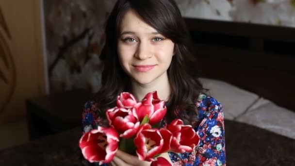 Mooie vrouw die lacht uitstrekken bloemen - tulpen naar de camera. — Stockvideo