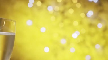 Sarı şenlik arka planında parıldayan parlak Noel ışıkları üzerinde ışıldayan iki şampanya kadehi. Yavaş çekim videosu 100fps. Yüksek kalite 4k görüntü