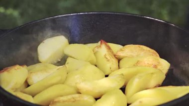 Tavada buharlaşan altın kavrulmuş patates dilimleri, çıtır çıtır kahverengi kenarlar ve yumuşak merkezler, cızırdayan tavaya yakın çekim,