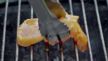 Izgarada marine edilmiş tavuk maşayla, salamura damlatarak ve dumanla, cızırdayan temasla yerleştiriliyor.