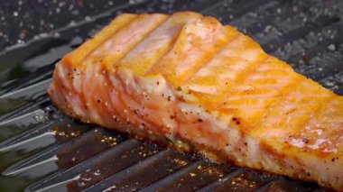 Dökme demir tavada pişen sulu somon bifteğinin yakın çekimi. Sağlıklı beslenme konsepti. Yüksek kalite 4k görüntü