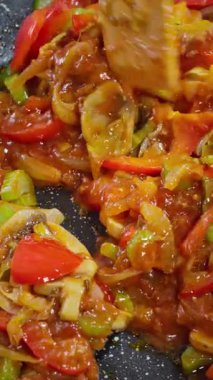 Mantarlı cızırtılı sebze kızartma tavası, kırmızı dolma biberi, soğan, kereviz, sarımsaklı parlak domates sosu, sıcak tavada karıştırılmış ahşap spatula, karamelize kenarları, canlı ağır çekim video fps