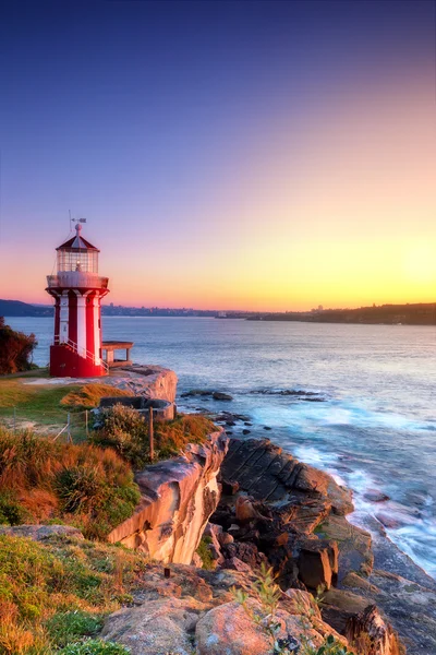 Sunrise deniz manzarası ve kırmızı-beyaz deniz feneri.