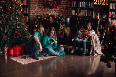 Üç çocuklu bir aile Noel ağacı süsler.