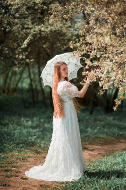 Parkta beyaz elbiseli ve şemsiyeli bir kız.