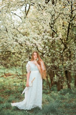 Parkta beyaz elbiseli ve şemsiyeli bir kız.