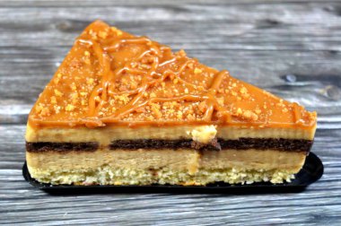 Biscuit creamy cake with layers of cake, whipped cream, biscuit paste and chocolate, a triangular piece of cake, celebration and holidays concept