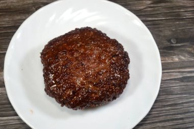 Biftekten yapılmış pişmiş hamburger köftesi, bir kıyma diski, tipik baharatlı, kıyma etinden yapılmış, sığ yağda kızartılmış, pişirilmiş et burgeri.