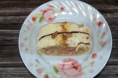 İsviçre usulü bir pasta dilimi, jöleli pasta, kremalı sarı ya da açık kahverengi bir sünger, ve üzerine fındık serpiştirilmiş beyaz çikolata tabakası, bir sünger İsviçre dürümü gateaux.