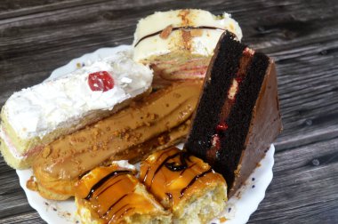 Çeşitli kapılar, çikolatalı pasta, beyaz orman pastası, bisküvi katmanlı ekler, beyaz çikolata katmanlı İsviçre dürümü ve krem şanti ile kaplanmış, üzeri karamel kaplı Sünger keki.