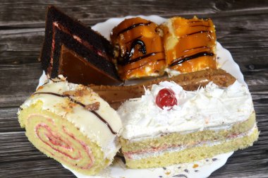 Çeşitli kapılar, çikolatalı pasta, beyaz orman pastası, bisküvi katmanlı ekler, beyaz çikolata katmanlı İsviçre dürümü ve krem şanti ile kaplanmış, üzeri karamel kaplı Sünger keki.