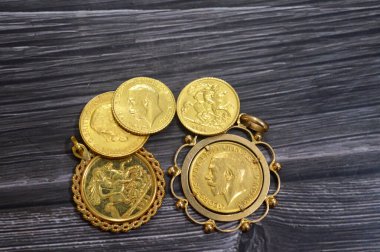 Kral V. George altın sikkeleri yığını, Kral V. George 'un ters yönde sola bakan portresini ve klasik St. George ve Ejderha' nın ters yönde, altın varlık yatırımı ve piyasa fiyatını içerir.