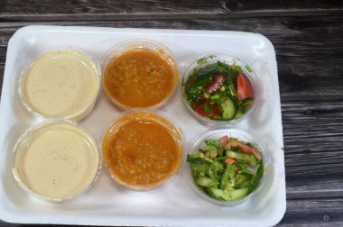 Tahini Tahina 'nın çeşitli salataları, kavrulmuş susamlı Orta Doğu çeşnisi, salatalık, domates, roket ve sığır ciğeri salatası dilimli yeşil salata.