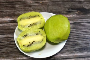 Soyulmuş Kiwifruit kivi, yumuşak kahverengi teni, parlak yeşil ya da altın eti, küçük siyah tohumları ve tatlı tart aromasıyla tanınan ahşap sarmaşıklardan yapılmış yenilebilir bir meyve.