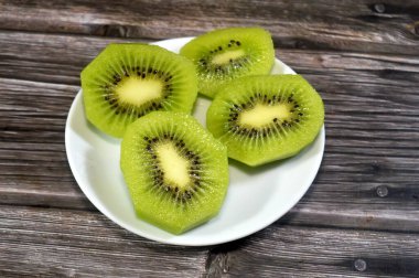 Kiwifruit kivi dilimleri, odunsu sarmaşıklardan yenebilir bir dut, tüylü kahverengi deri, parlak yeşil et, küçük siyah tohum ve tatlı tart aromalı, C vitamini, lif ve antioksidanlarla dolu.