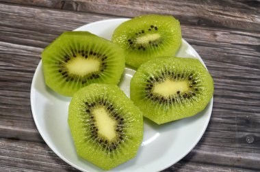 Kiwifruit kivi dilimleri, odunsu sarmaşıklardan yenebilir bir dut, tüylü kahverengi deri, parlak yeşil et, küçük siyah tohum ve tatlı tart aromalı, C vitamini, lif ve antioksidanlarla dolu.