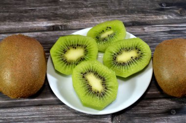 Kiwifruit kivi dilimleri, odunsu sarmaşıklardan yenebilir bir dut, tüylü kahverengi deri, parlak yeşil et, küçük siyah tohum ve tatlı tart aromalı, C vitamini, lif ve antioksidanlarla dolu.