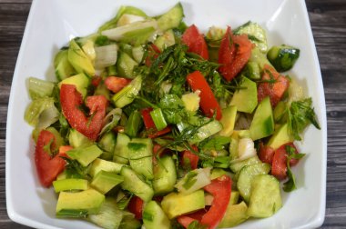 Bir tabak yeşil salata, taze domates, salatalık, yeşil soğan, avokado, dereotu, maydanoz, marul, yeşil biber ve pırasa, taze sebzeli sağlıklı yeşil salata.