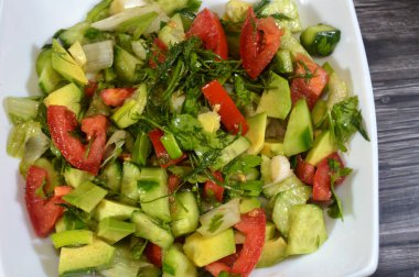 Bir tabak yeşil salata, taze domates, salatalık, yeşil soğan, avokado, dereotu, maydanoz, marul, yeşil biber ve pırasa, taze sebzeli sağlıklı yeşil salata.