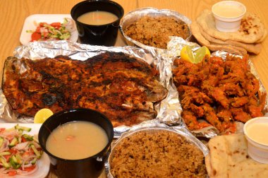 Baharatlı sos, limon, Tilapia, Sinjari Balıkları, Mısır balıklı pilav, pide, Tahini ve yeşil salata ile karıştırılmış çıtır çıtır karides deniz mahsulleri.