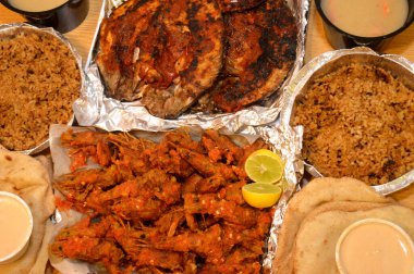 Baharatlı sos, limon, Tilapia, Sinjari Balıkları, Mısır balıklı pilav, pide, Tahini ve yeşil salata ile karıştırılmış çıtır çıtır karides deniz mahsulleri.