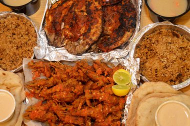 Baharatlı sos, limon, Tilapia, Sinjari Balıkları, Mısır balıklı pilav, pide, Tahini ve yeşil salata ile karıştırılmış çıtır çıtır karides deniz mahsulleri.