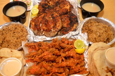 Baharatlı sos, limon, Tilapia, Sinjari Balıkları, Mısır balıklı pilav, pide, Tahini ve yeşil salata ile karıştırılmış çıtır çıtır karides deniz mahsulleri.