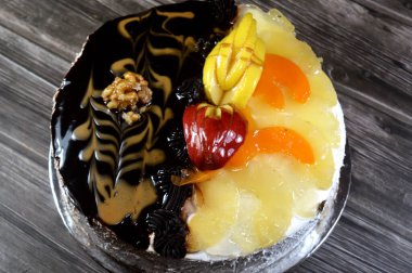 İki ayrı parçadan oluşan doğum günü pastası kutlamalar için süngerimsi kremalı pasta, koyu çikolata, karamel, vanilyalı krema, ananas dilimleri, elma, şeftali