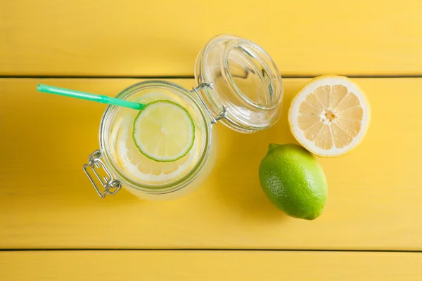Lemonad med is, citron och lime i en burk på en gul trä ba — Stockfoto