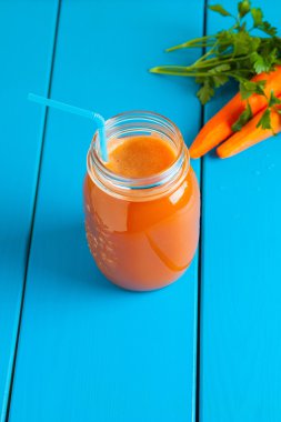 Mavi ahşap zemin üzerinde bir kavanoza sağlıklı havuç güler yüzlü.