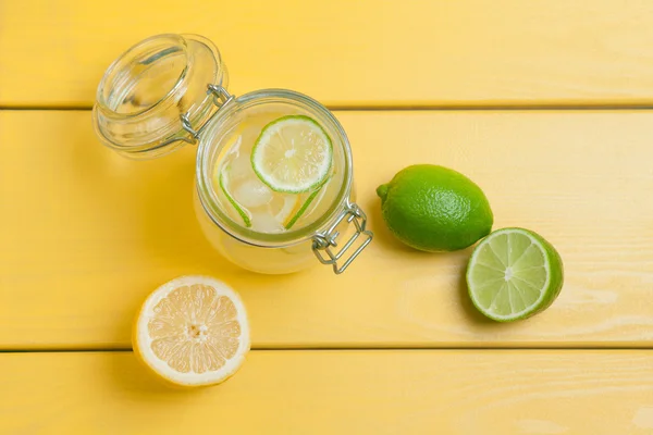 Buz, limon ve kireç üzerinde sarı bir ahşap ba bir kavanoza ile limonata — Stok fotoğraf