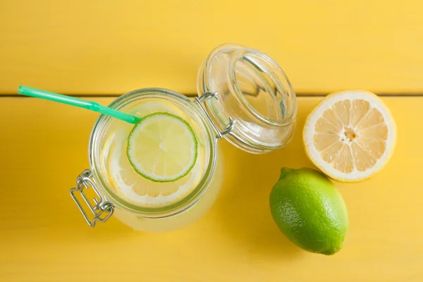 Buz, limon ve kireç üzerinde sarı bir ahşap ba bir kavanoza ile limonata — Stok fotoğraf