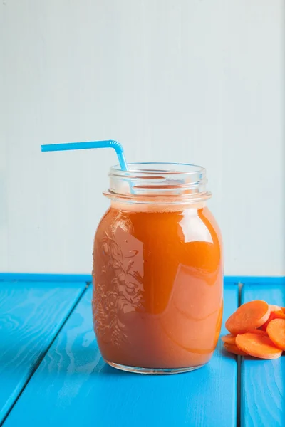 Mavi ahşap zemin üzerinde bir kavanoza sağlıklı havuç güler yüzlü.