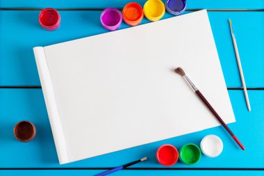 Albüm sayfaları ve boya, fırça bir mavi ahşap arka plan üzerinde.