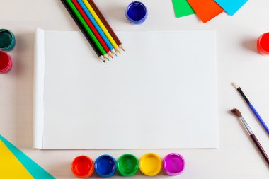 Beyaz ahşap backgro üzerinde albüm sayfaları ve boya, kalem, fırça