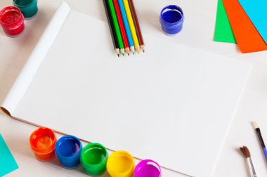 Beyaz ahşap backgro üzerinde albüm sayfaları ve boya, kalem, fırça