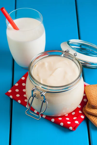 Mavi ahşap bir masa üzerinde ev yapımı yoğurt.